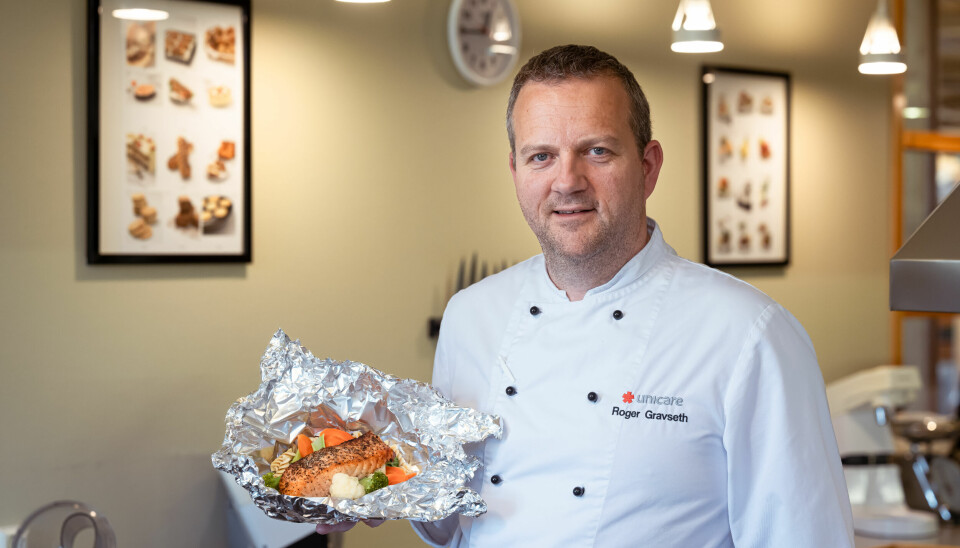 Kjøkkensjef Roger Sundt Gravseth ved Unicare på Røros holder en foliepakke med laks og grønsaker i hånda.
