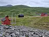 Oversiktsbilde fra Killingdal gruve med et kapell og to andre bygninger, grønt gress og åpne vidder. høyfjell
