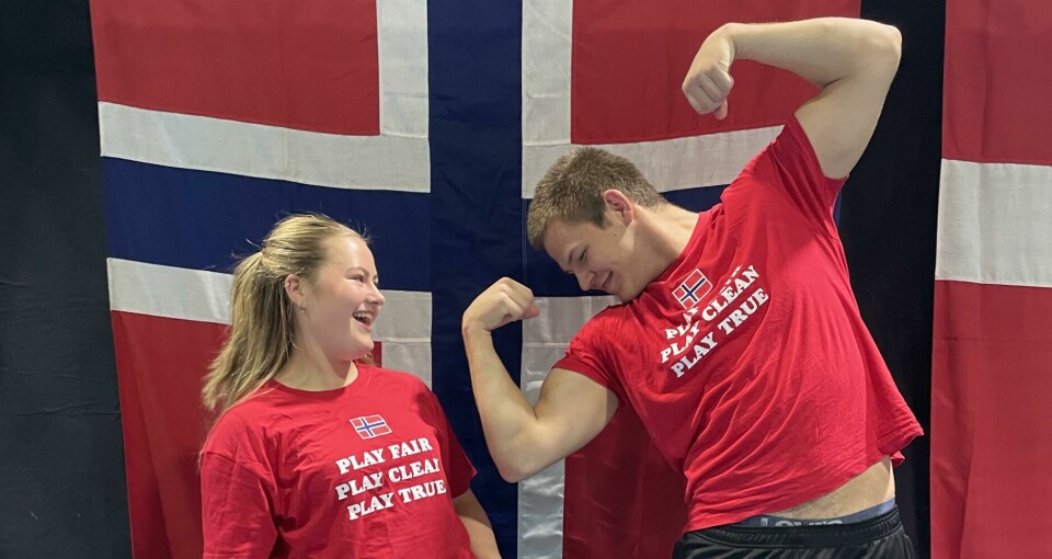 To gullvinnere foran det norske flagget i humoristisk positur