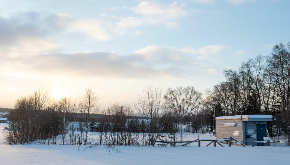 Vinterbilde mes sol, snø og blå himmel av inngjerdet område og brakka til hundeklubben