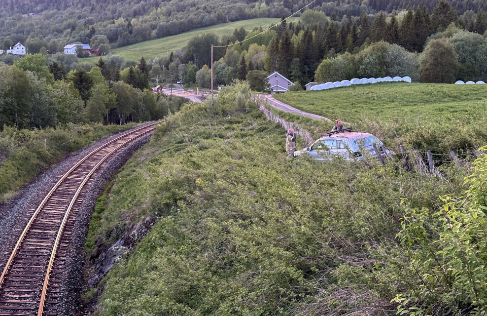 TETT PÅ: Det var ikke mange metrene om å gjøre at bilen havnet på jernbanelinja. Lokalt brannvesen undersøkte raskt tilstanden på kjøretøyet. I bakgrunnen skimtes Ålen stasjon.