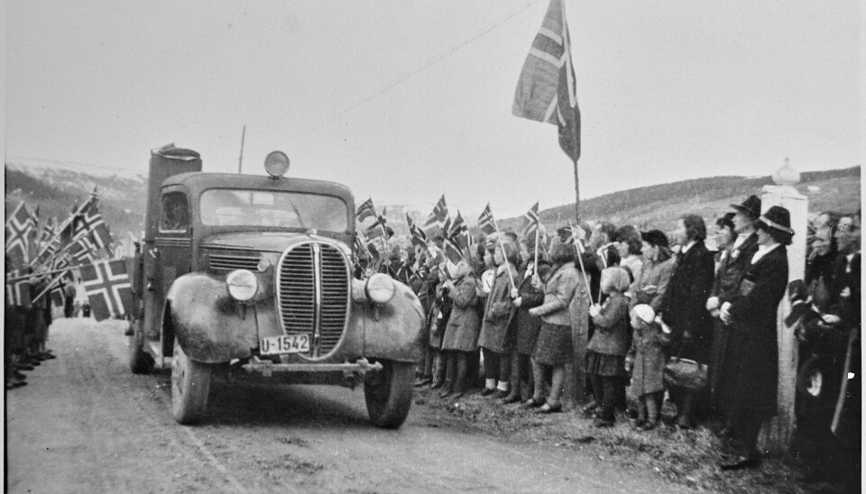 Lastebil med knottgenerator ankommer til Ålen kirke 17. mai 1945. Alle var ute og feiret. Kirka hadde ikke plass til alle som ville høre sokneprest Bentzen forrette, så det ble satt ut høyttalere på kirkebakken for at alle skulle få med seg prekenen. Kilde: Trøndelag Folkemuseum.