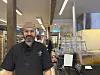 Baker i sort arbeidsantrekk smilende bak disken i et lyst bakeri på Røros.