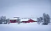 Røde bygninger omgitt av snødekt landskap og trær en vinterdag.