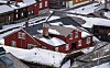 Snødekte, røde og brune trehus tett i tett i et vinterlig bymiljø. Teknisk etat Røros kommune.
