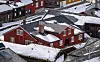 Snødekte, røde og brune trehus tett i tett i et vinterlig bymiljø. Teknisk etat Røros kommune.