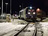 Persontog kjører inn på snødekt stasjon i mørket