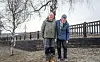 To eldre menn står sammen foran et gjerde og en bjørk på en overskyet dag.