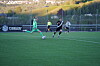 Fotballspillere i grønt og svart løper på en kunstgressbane under en kamp.