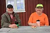 Terje og Randi Hasvoldseter sitter ved et utebord foran en rød bygning med kopper og småbakst.