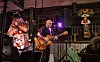 To musikere spiller gitar og synger på en liten scene.
